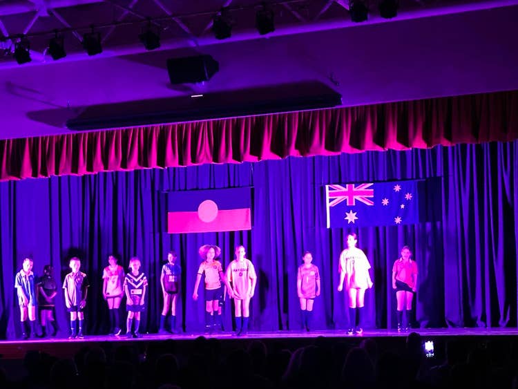 Students in costume on stage under red/purple lighting performing 'Back to Cambewarra' the musical.