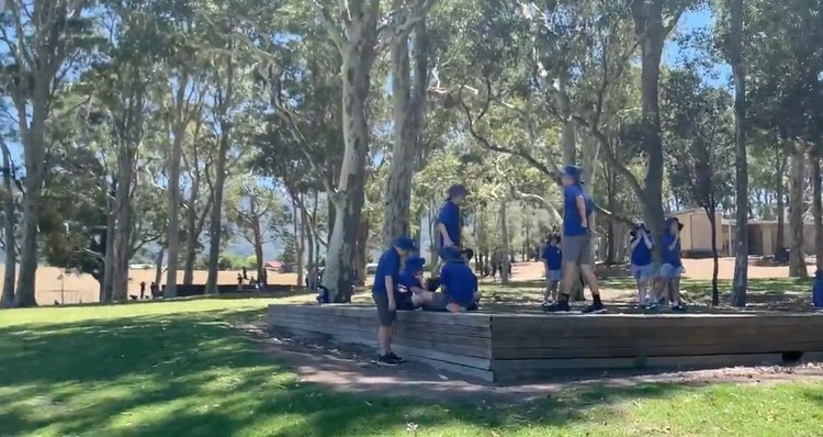 A group of students in uniform playing under the trees on the raised pods